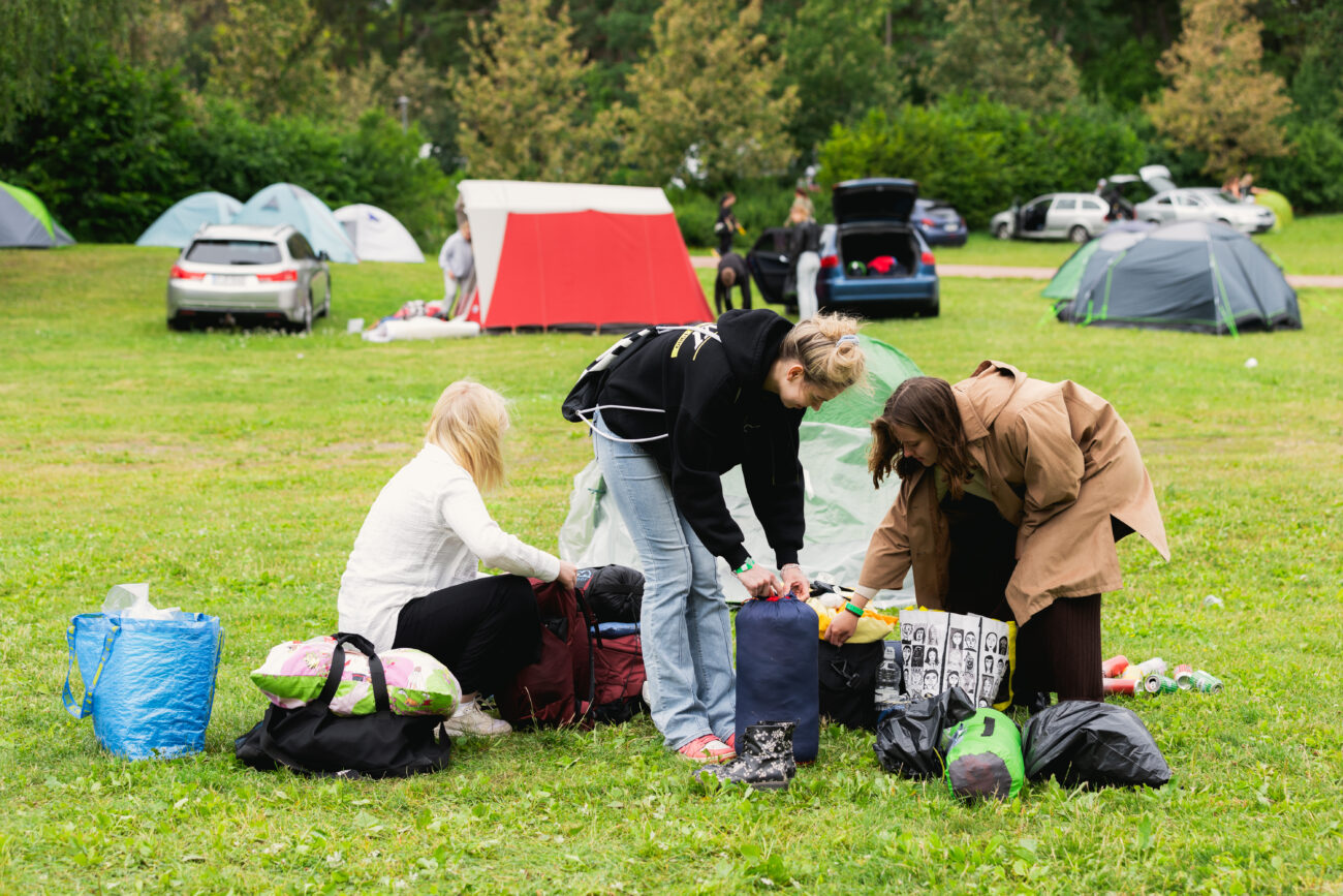 Kolme tyttöä purkaa leiriytymistarvikkeitaan Ruisrockin leirinnässä.